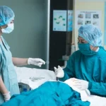 Ophthalmologists exchanging instruments during cataract surgery.