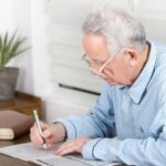 An older adult sitting down to solve a crossword puzzle.