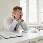 Man with his head in his hands at his desk