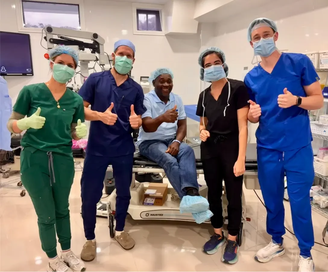 Dr. Passi and team posing with happy patient in surgical room after eye procedure